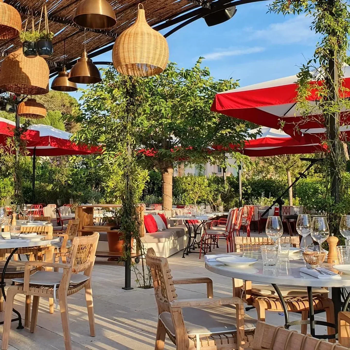 Outdoor dining at Beefbar Saint-Tropez, with red umbrellas and wooden decor.