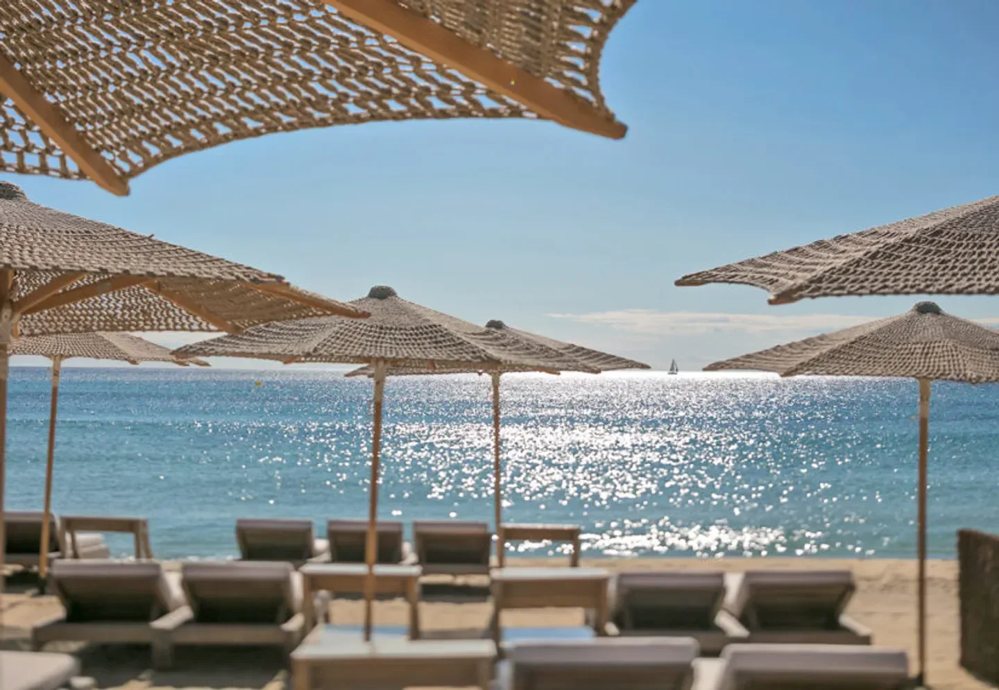 Beach umbrellas at Byblos Beach in Saint-Tropez with sunbeds and sparkling sea.