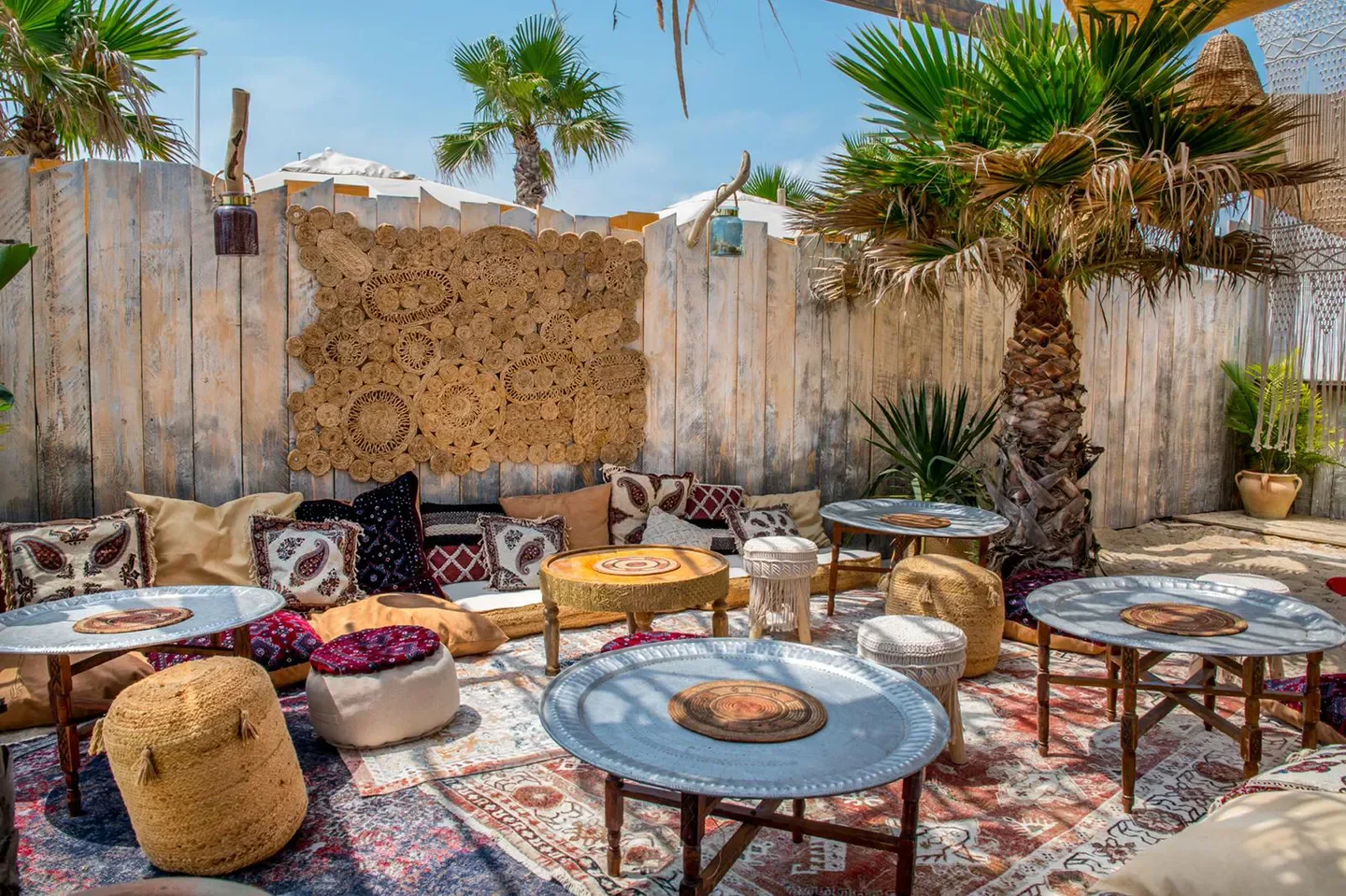 Casa Amor in Saint-Tropez: Bohemian beach club with comfortable seating and palm trees.