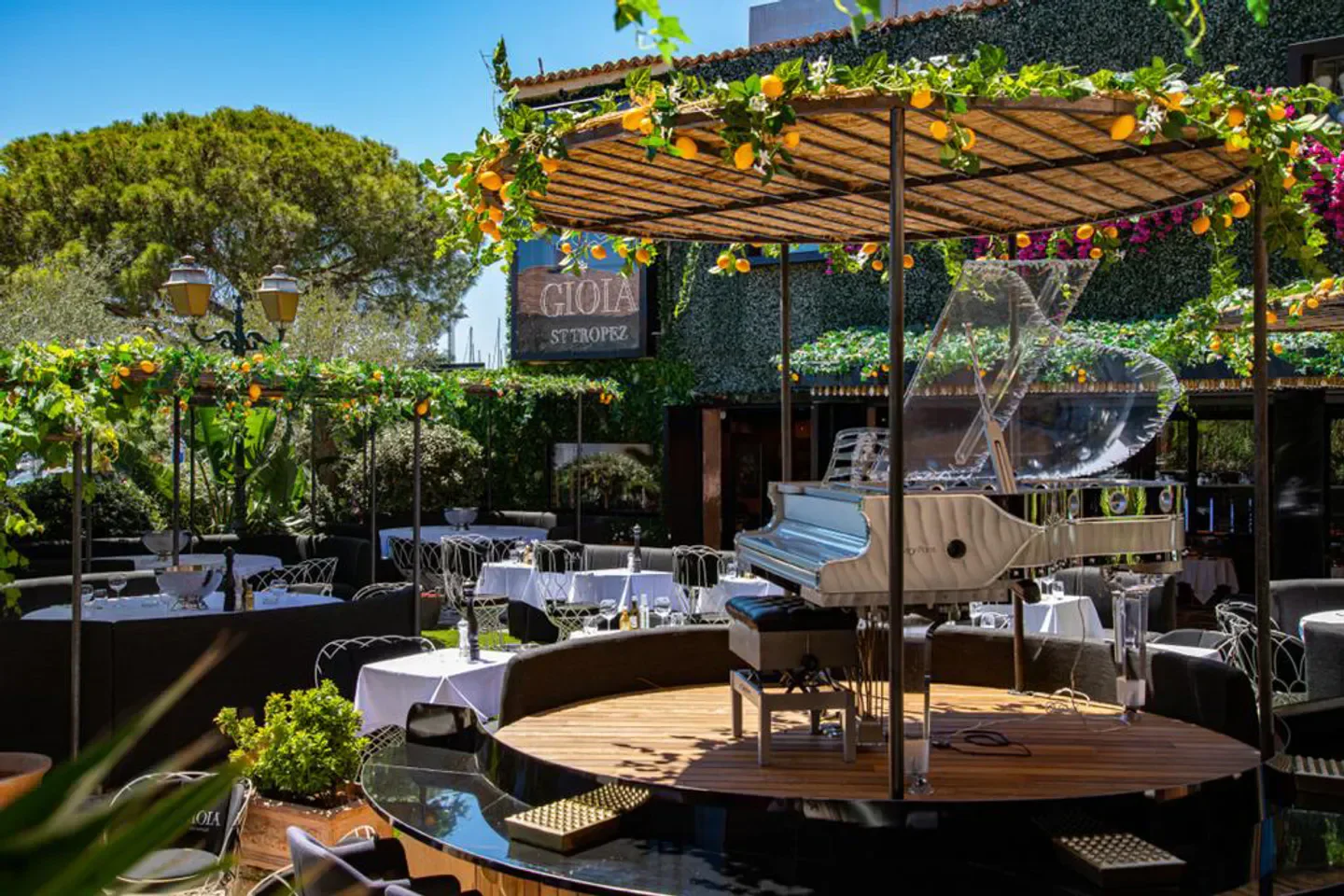 Elegant outdoor setting at Gioia restaurant in Saint-Tropez with piano and dining tables.