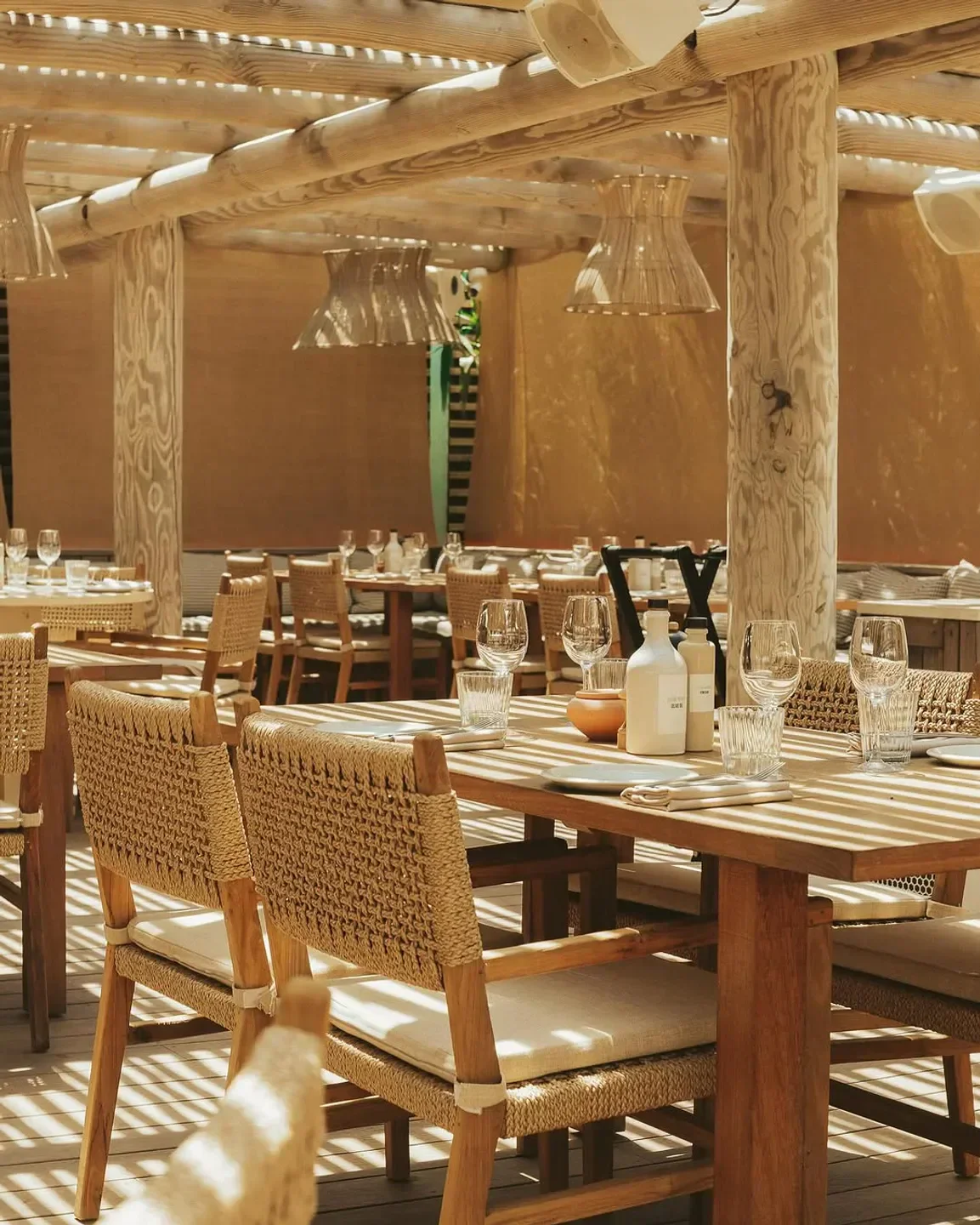 Dining area at Indie Beach in Saint-Tropez restaurant with woven chairs and wooden tables