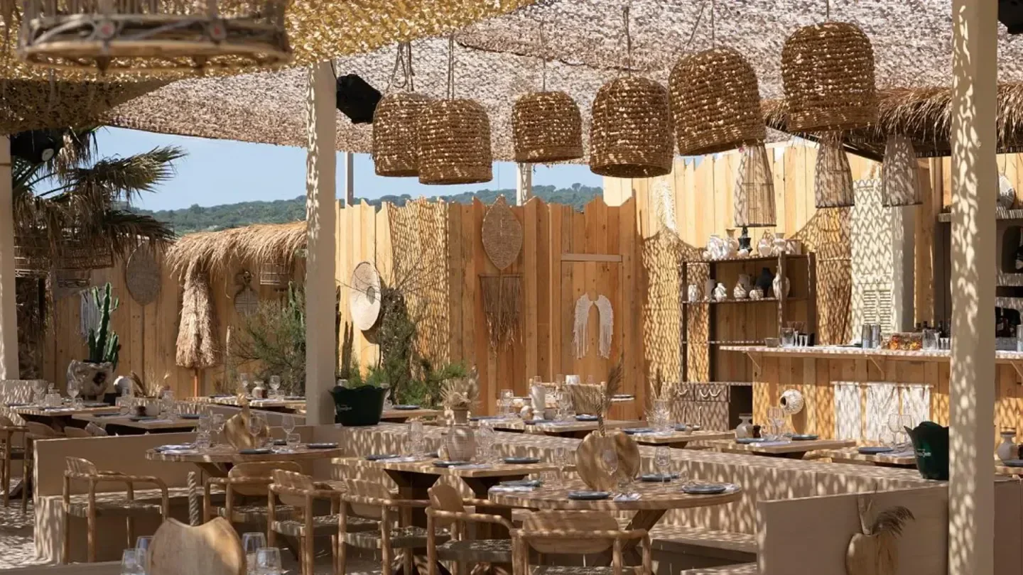 Restaurant Kalamata Beach in Saint-Tropez. Beachfront dining with rustic decor and woven lamps.