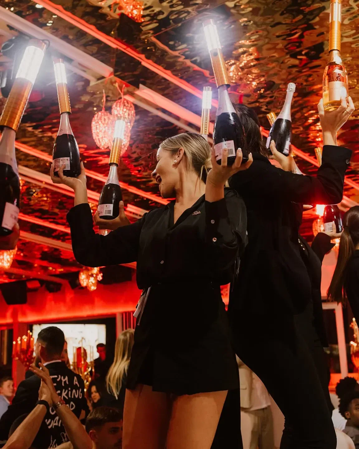 Champagne bottles held up at L'Opera nightclub in Saint-Tropez, a lively and glamorous scene.