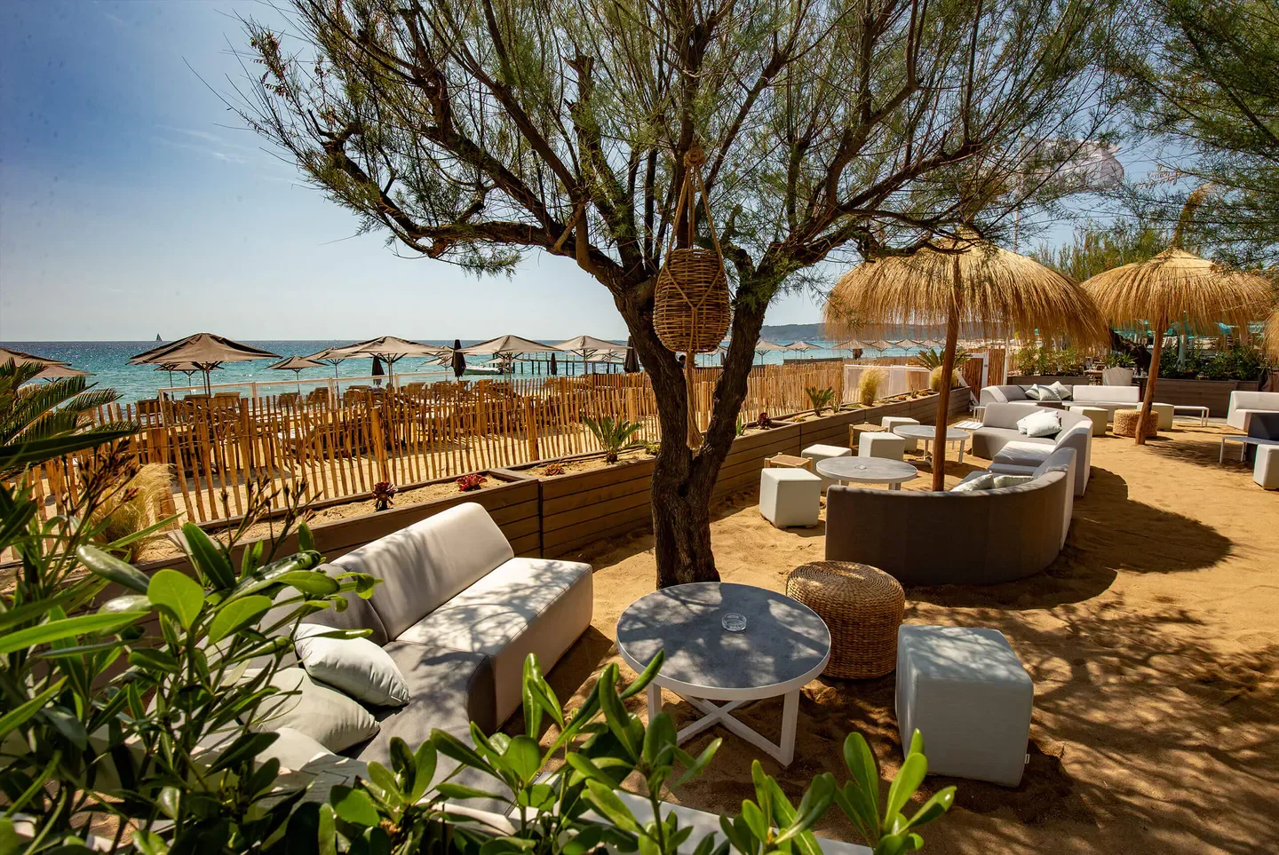 Outdoor seating at Moorea Plage restaurant in Saint-Tropez, with beach views and thatched umbrellas