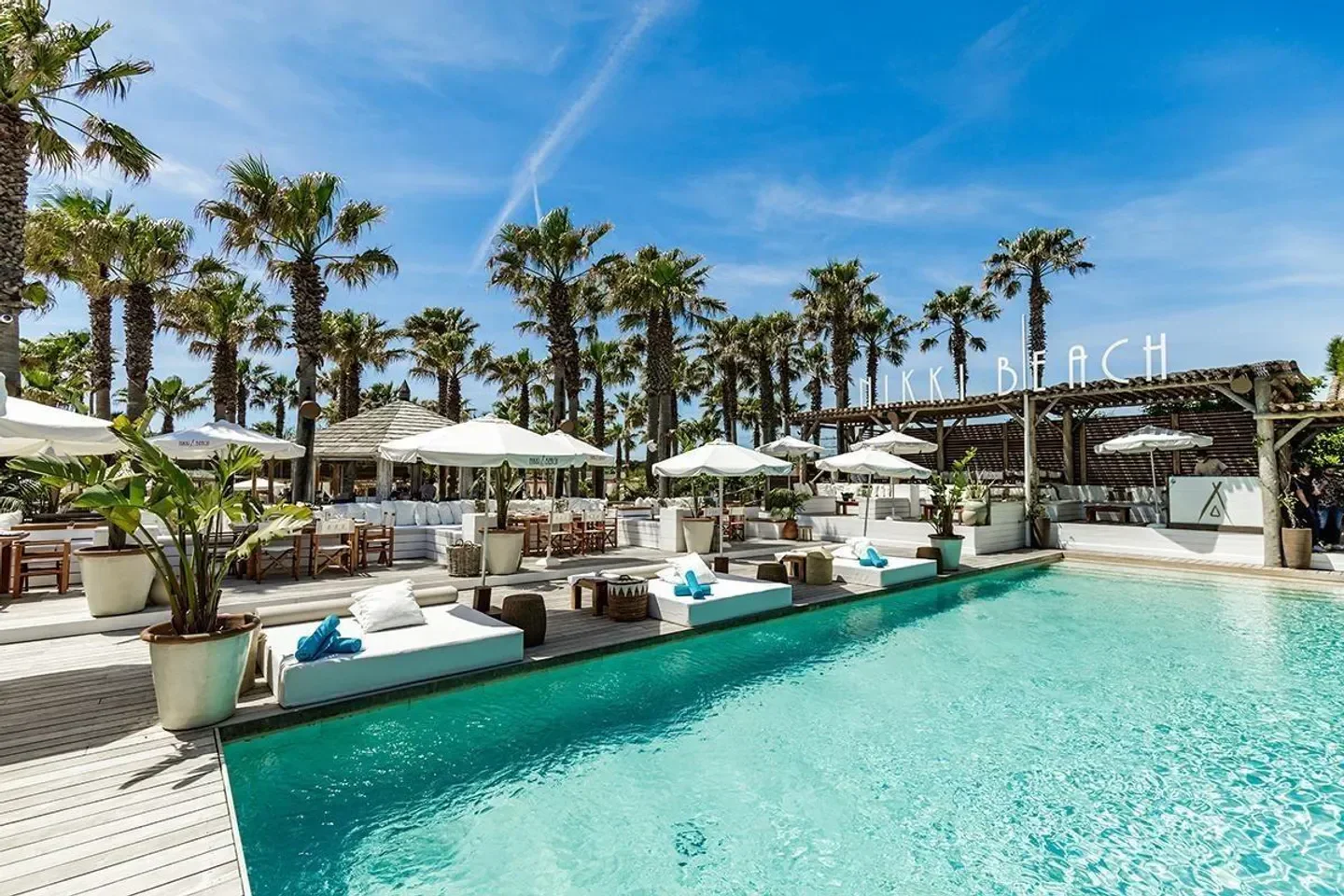 Pool and lounge area at Nikki Beach Saint-Tropez beach club with palm trees