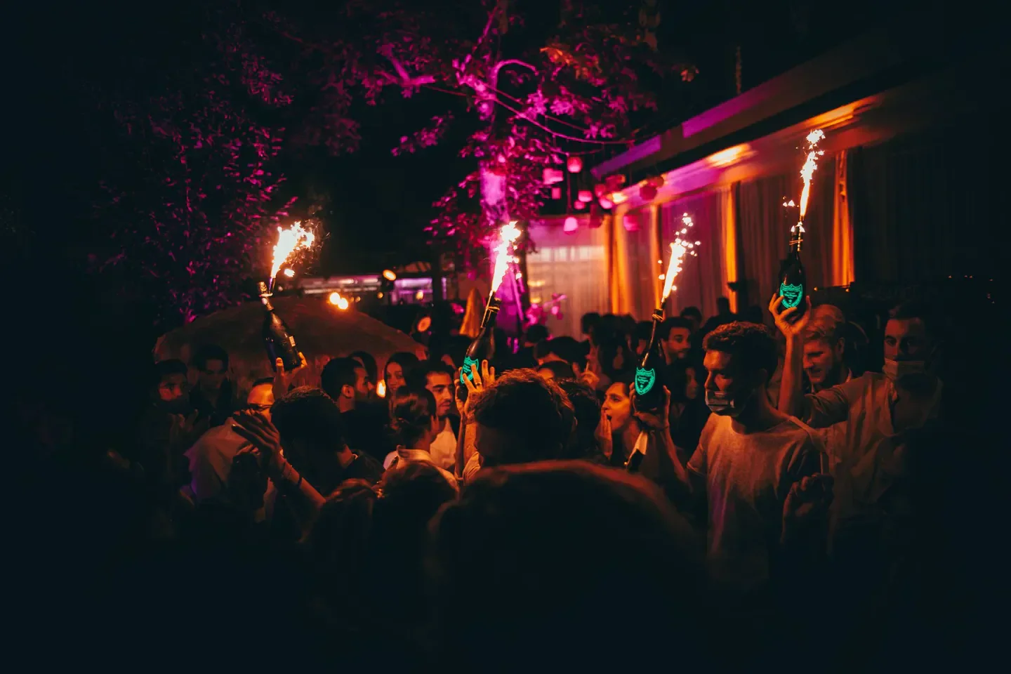 Sanctum nightclub in Saint-Tropez. People celebrating with sparklers and bottles at night.