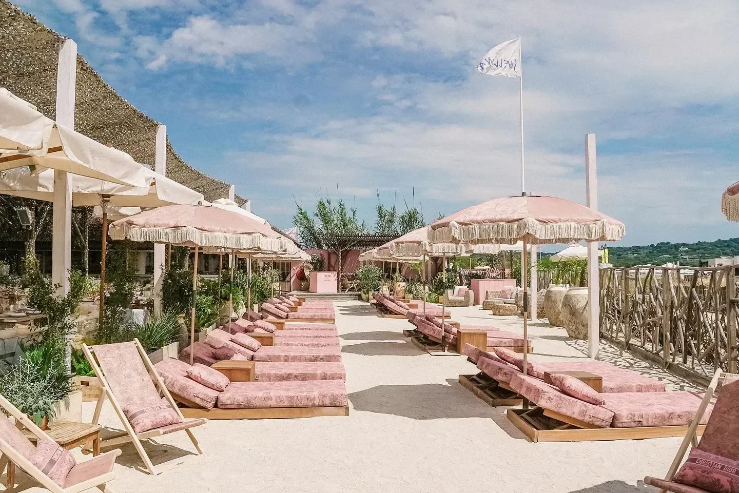 Shellona beach club in Saint-Tropez with pink sunbeds and parasols under a bright sky.