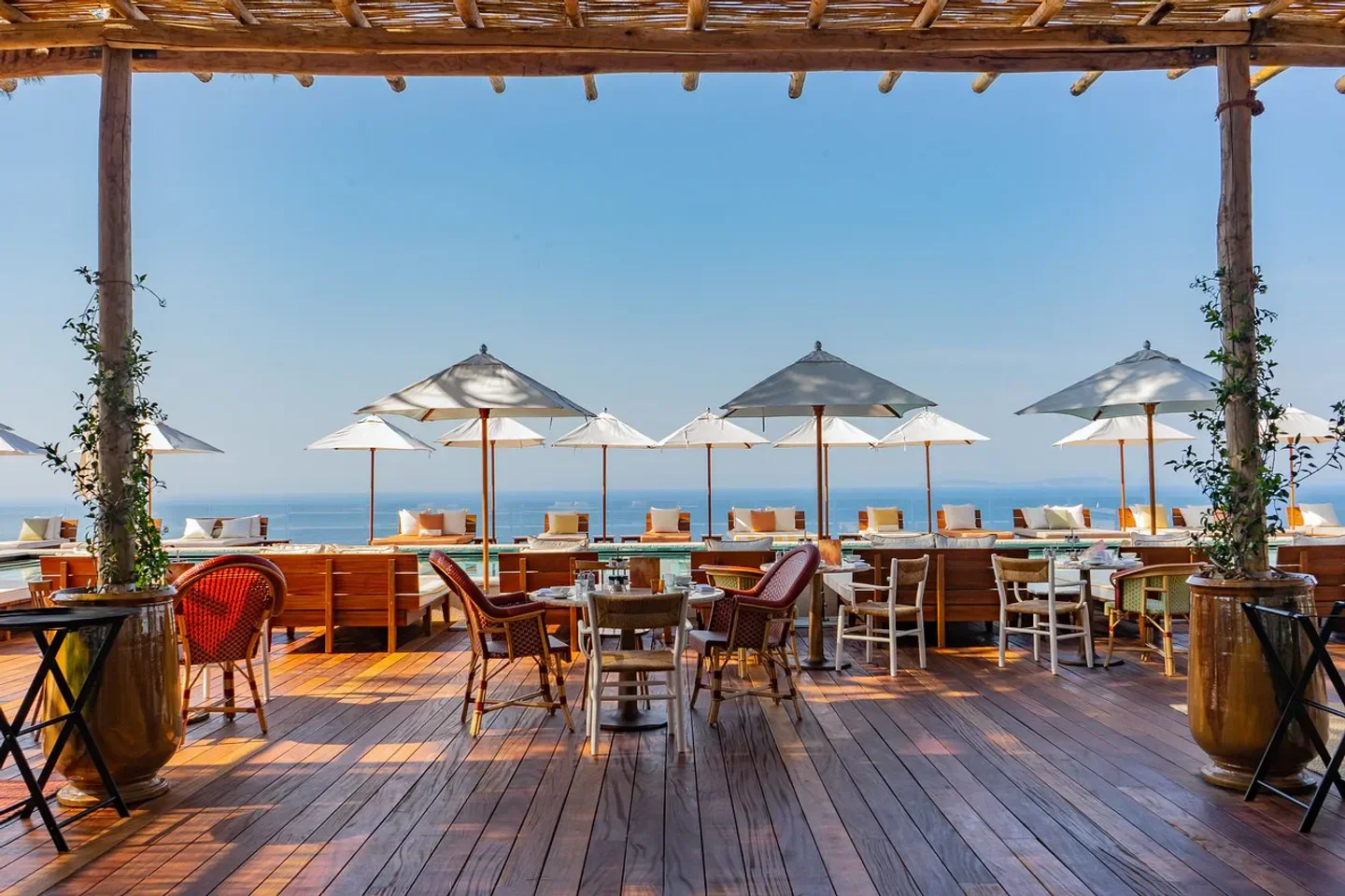 Outdoor dining at Vista restaurant in Saint-Tropez, with ocean views and wooden deck.